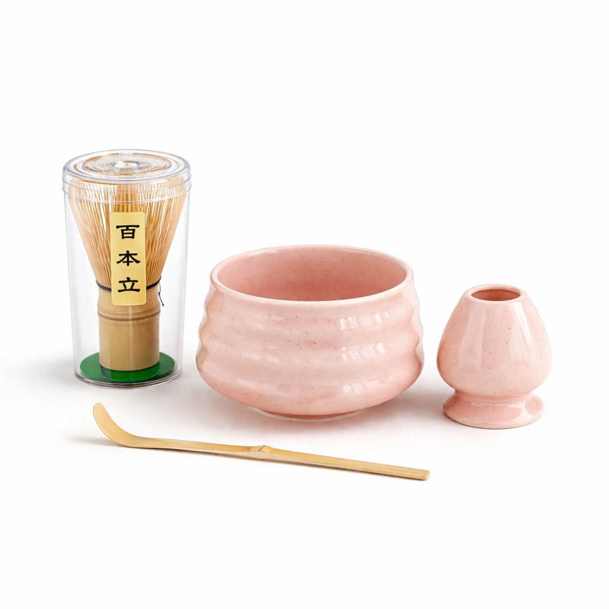 The Różowy zestaw matcha 4 elementy includes a pink ceramic bowl, whisk holder, bambusowa miotełka in a clear container, and bamboo scoop—ideal for a minimalist matcha ceremony on a white background.
